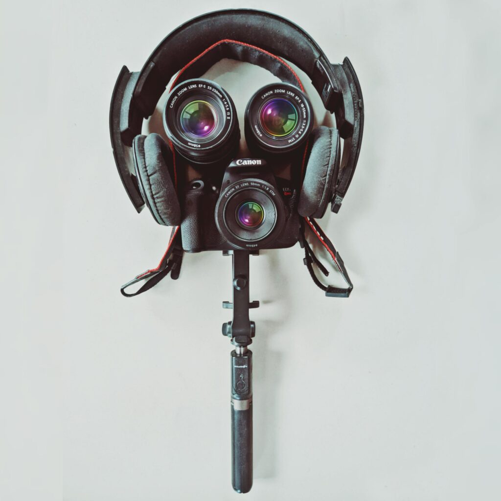 Artistic arrangement of a camera and headphones resembling a face on a white background.